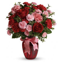 Red roses and pink carnations in a red vase with a pink ribbon