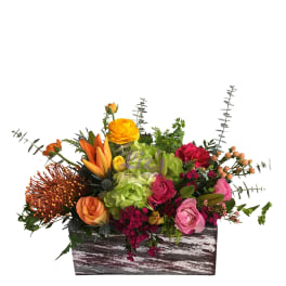 Mixed floral arrangement in a rustic wooden box with orange, pink, and green blooms