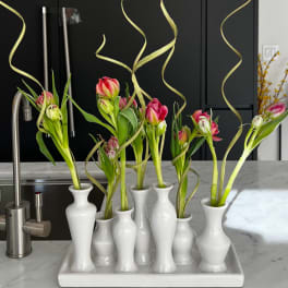 Pink tulips in white bud vases on a tray