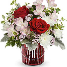 Red roses and pale pink flowers in a red glass vase