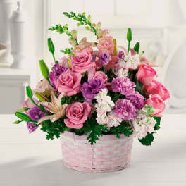 Pink and purple mixed flower arrangement in a pink basket