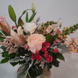 Mixed bouquet with roses, lilies, and pink spray flowers in a vase