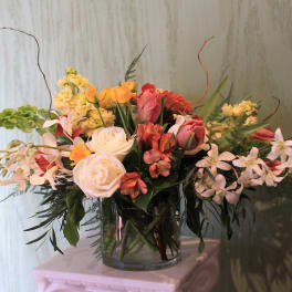 Mixed bouquet of roses, orchids, and lilies in a glass vase