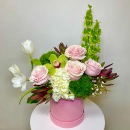 Pink roses and white tulips arranged in a pink hat box