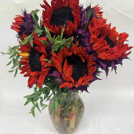 Bouquet of red and purple sunflowers in a glass vase