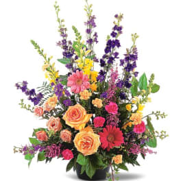 Mixed bouquet of roses, gerbera daisies, carnations, and purple spikes in a black vase
