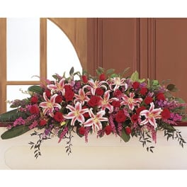 Long floral arrangement with red roses and pink lilies in a white container