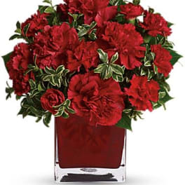 Red carnations arranged in a clear square vase