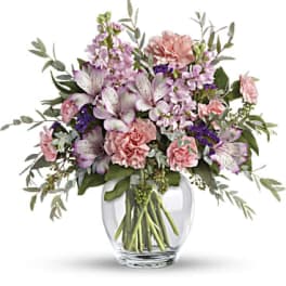 Pink and lavender flowers arranged in a clear glass vase