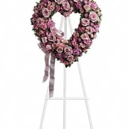 Heart-shaped pink rose wreath on a white easel with ribbon