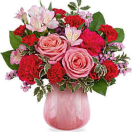 Pink roses and red carnations in a pink glass vase