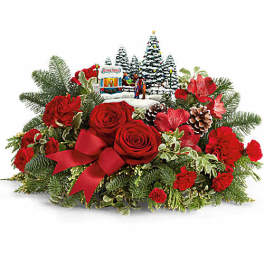 Red roses and carnations arranged with a ribbon and holiday village centerpiece