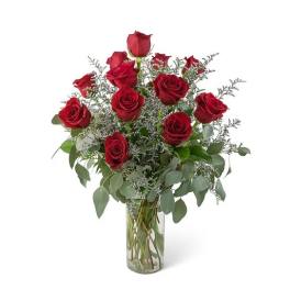 Red roses arranged in a clear glass vase with airy filler