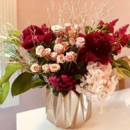 Bouquet of red and blush flowers in a metallic vase