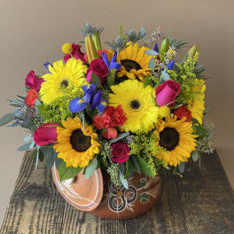Bright mixed bouquet with sunflowers, gerbera daisies, roses, and irises in a decorative pot