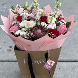 Mixed bouquet of pink, red, and white flowers in pink wrap
