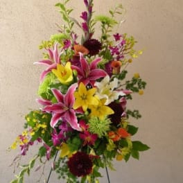 Tall mixed floral spray with pink lilies and yellow blooms on a stand
