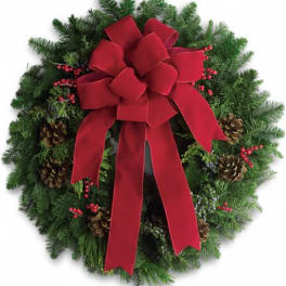 Evergreen wreath with a large red bow, pinecones, and red berries in a circular design