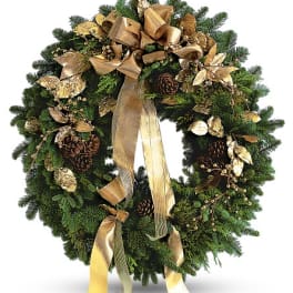 Evergreen wreath decorated with gold ribbon, pinecones, and metallic gold leaves and berries.