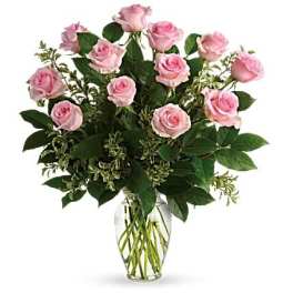 Arrangement of light pink roses with lush foliage in a clear glass vase