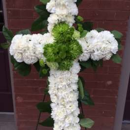 White and green floral cross arrangement on a stand