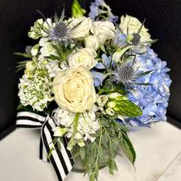 Bouquet of white roses and blue hydrangeas with thistle accents
