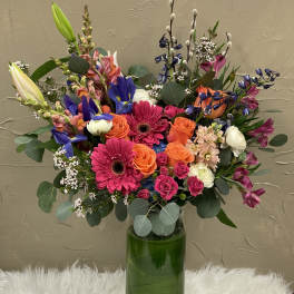 Colorful mixed bouquet in a tall green glass vase