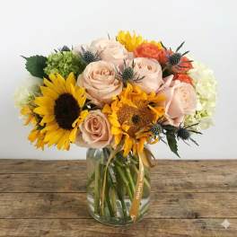 Bouquet of sunflowers and pale roses in a glass vase