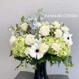 White roses and green hydrangeas in a dark blue vase