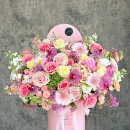 Large pink floral arrangement in a round pink box with a lace ribbon