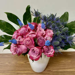 Pink roses and blue thistle in a white vase