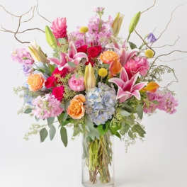 Mixed bouquet of pink, purple, and orange flowers in a clear glass vase