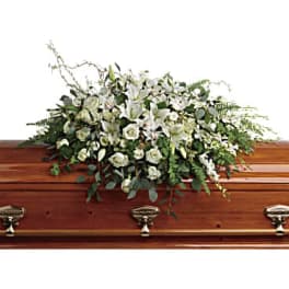 White floral casket spray on a wooden coffin