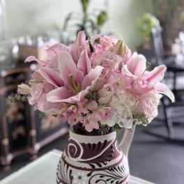 Pink lilies and roses arranged in a patterned vase