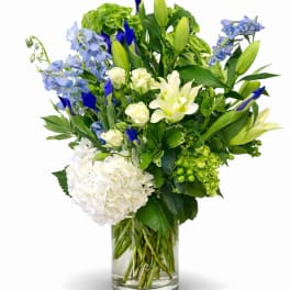 Blue and white mixed flower arrangement in a clear glass vase