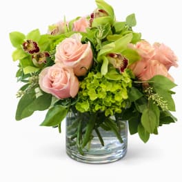 Pink roses and green orchids arranged in a glass vase