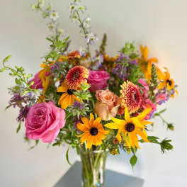 Mixed bouquet of pink roses and orange daisies in a glass vase