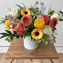 Mixed bouquet in a white vase with yellow, pink, white, and lavender flowers