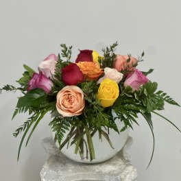 Mixed roses arranged in a round white vase