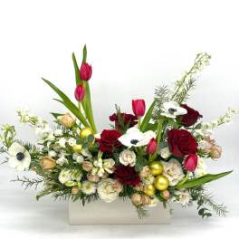 Low red and white floral arrangement with tulips, roses, anemones and gold ornaments in a white rectangular container