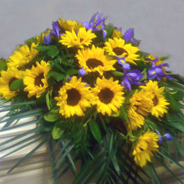 Yellow sunflowers and purple flowers arranged in a low spray