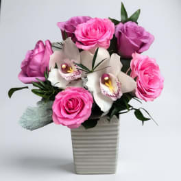 Pink roses and white orchids arranged in a ribbed vase
