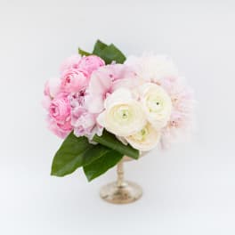 Pink and white floral arrangement in a small pedestal vase