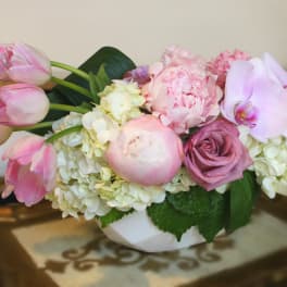 Pink tulips, roses, peonies, and orchids in a white bowl