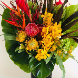 Tropical bouquet with red and yellow flowers in a black vase