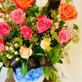 Bouquet of pink, orange, and white roses in a blue-and-white vase