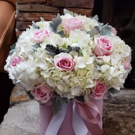 Pink roses and white hydrangeas in a pink hatbox with ribbon