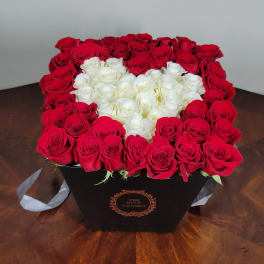 Heart-shaped box of red and white roses on a table