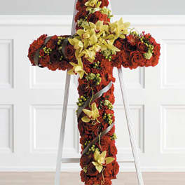 Standing cross-shaped spray of red flowers with yellow orchids on a white easel