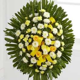 Round standing floral wreath with white and yellow flowers and yellow ribbon accents